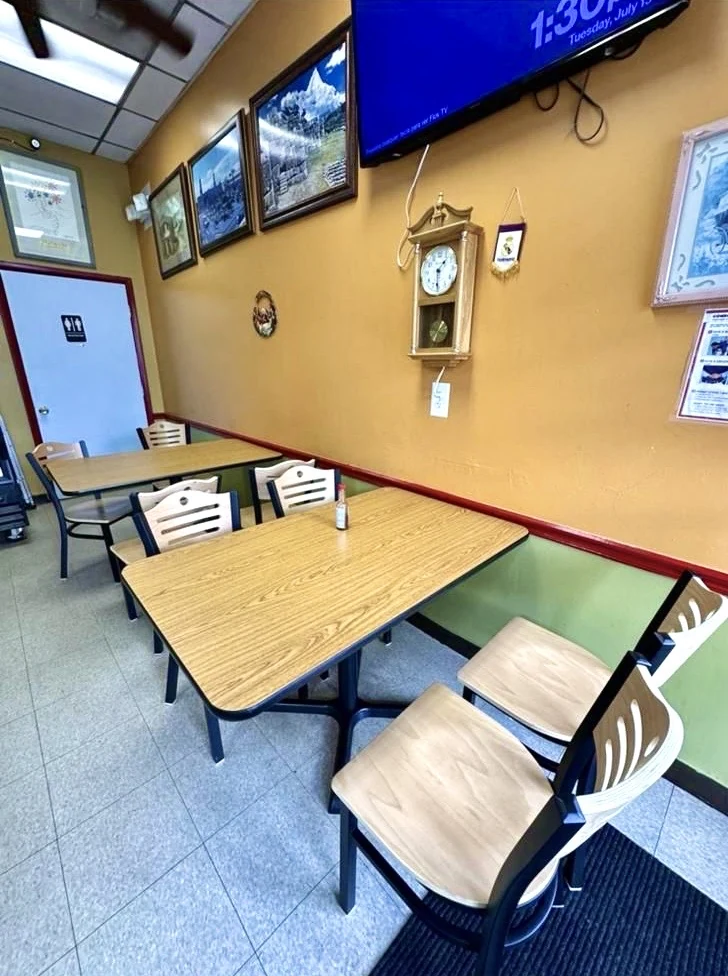 The restaurant’s dining area with woodgrain tables, pale chairs and yellow walls