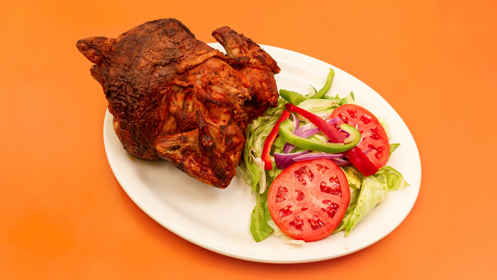 Whole roasted chicken and salad on a white plate